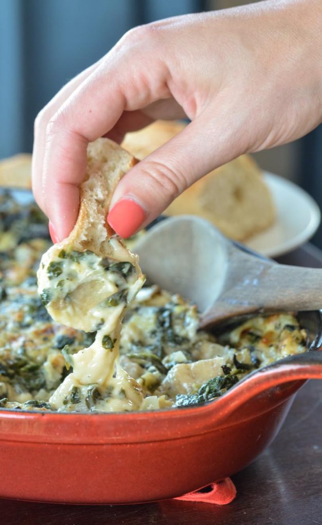 Grabbing a dip of artichoke dip with piece of bread.