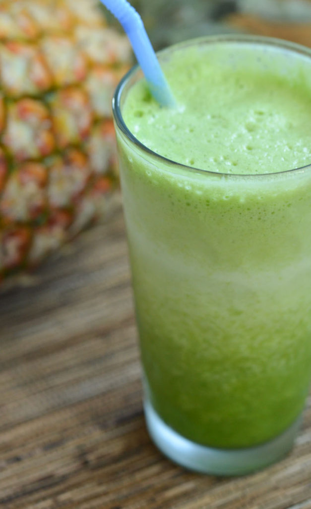 A tall glass of lower back pain relief green juice with blue straw.