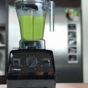 Green juice in a jar in front of a Vitamix A3500