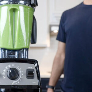 Green juice in a jar in front of a Vitamix A3500